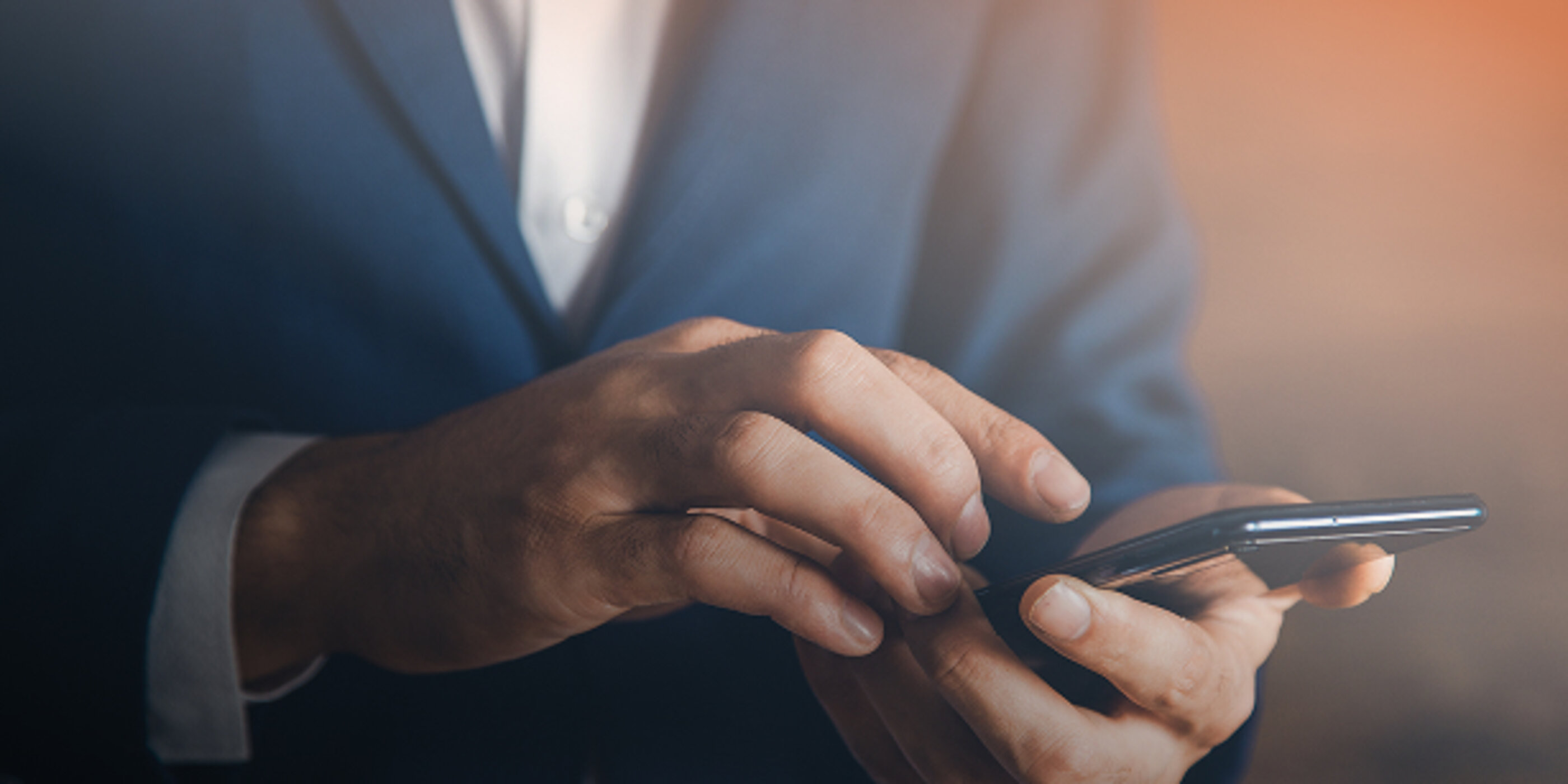 Mann im Anzug bei der Bedienung eines Smartphones